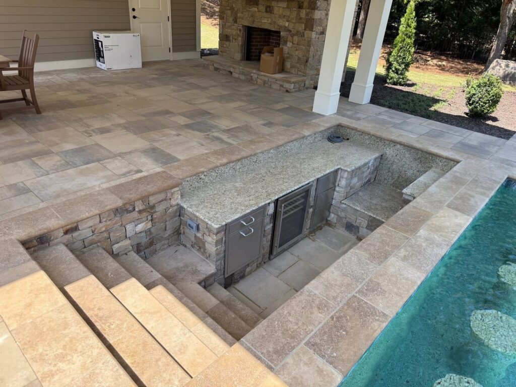 Poolside bar with built-in refrigerator and stone countertop.
