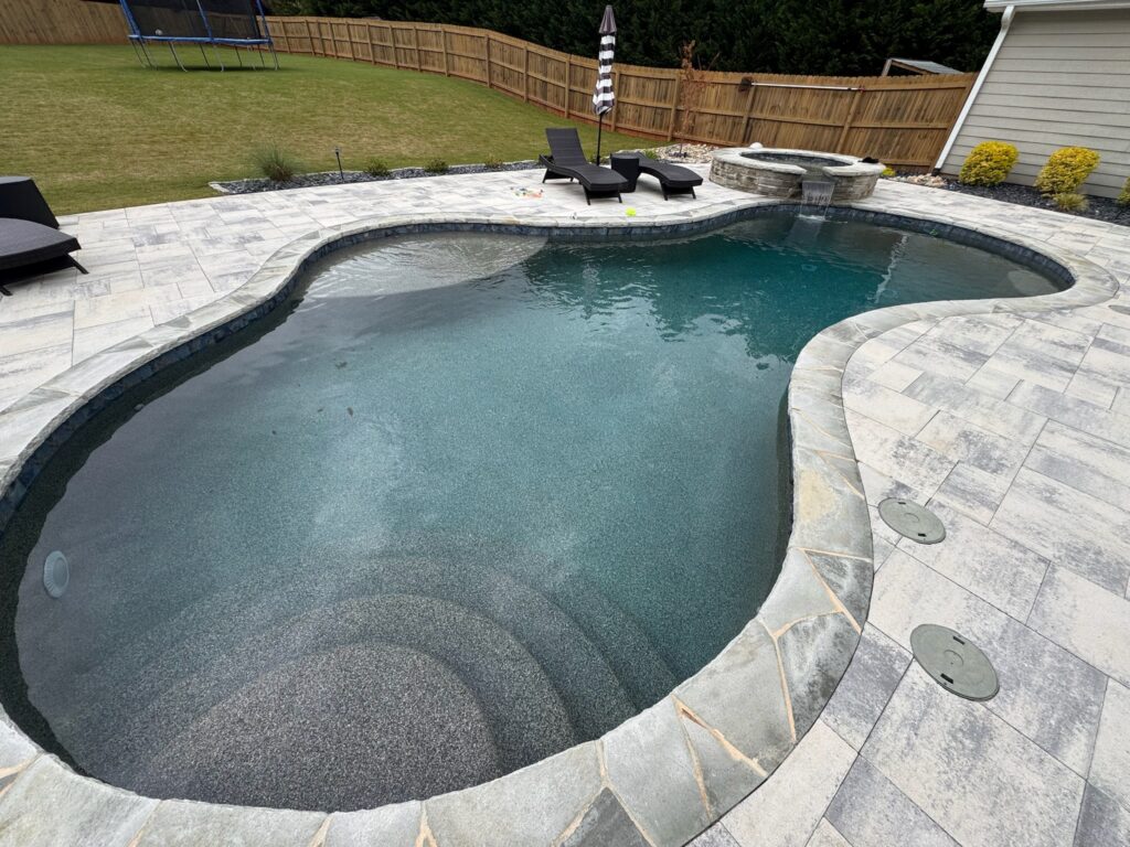 Beautiful backyard pool with stone border and lounge chairs.