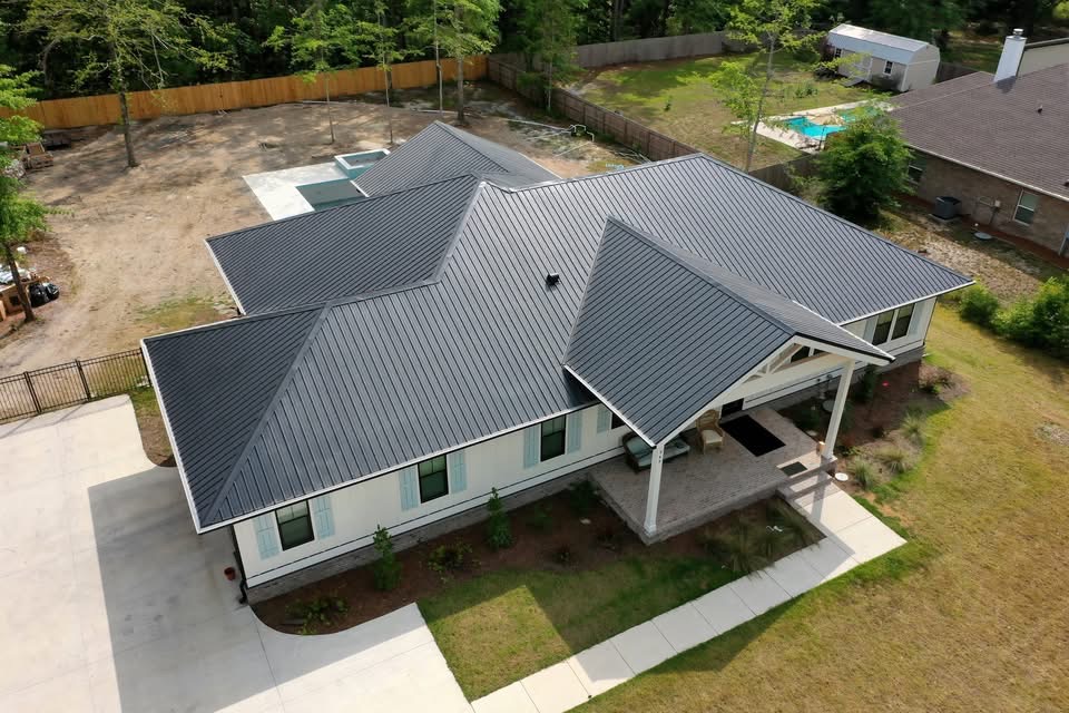 Aerial view of a house with a metal roof and landscaped yard.