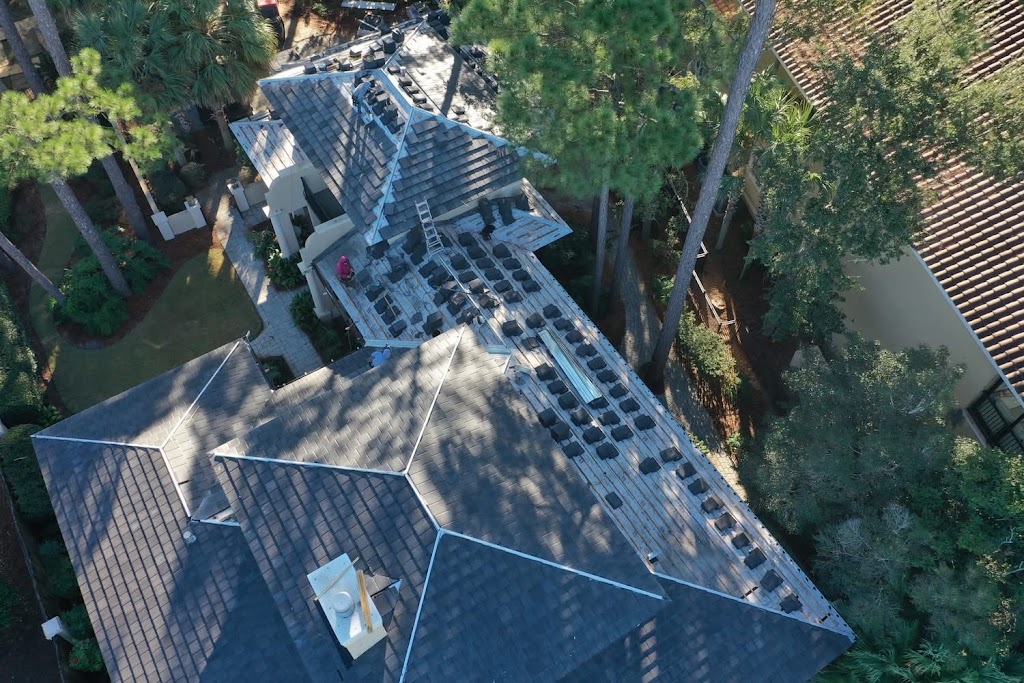 Aerial view of a house with a tile roof with surrounding trees.